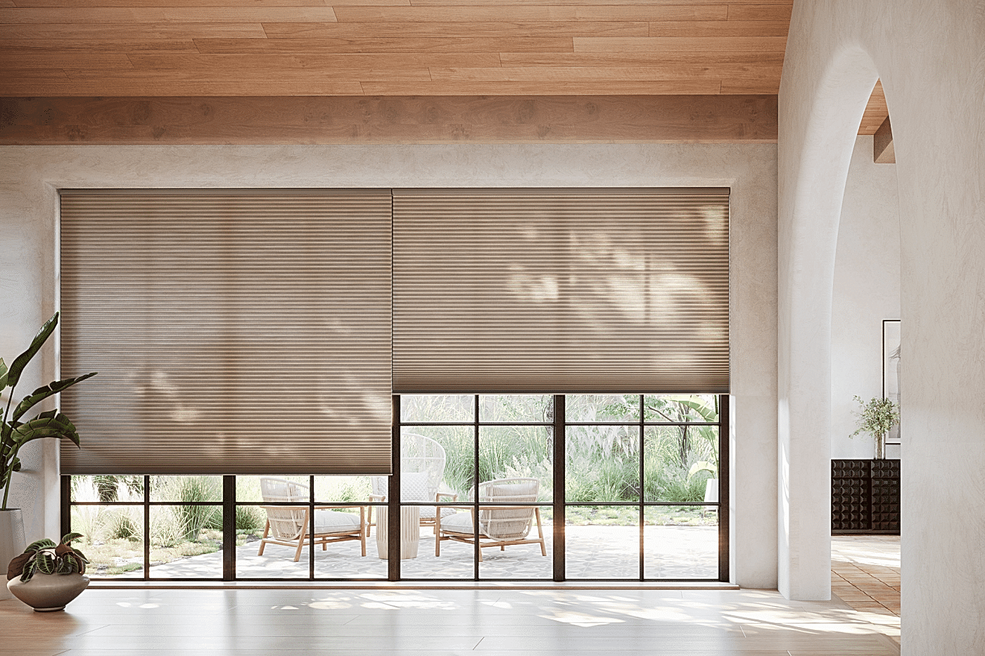 applause-vintage-honeycomb-shades-large-window-wall Two large Applause honeycomb shades in a neutral taupe color covering an expansive floor-to-ceiling window wall with black steel frames in a modern living room