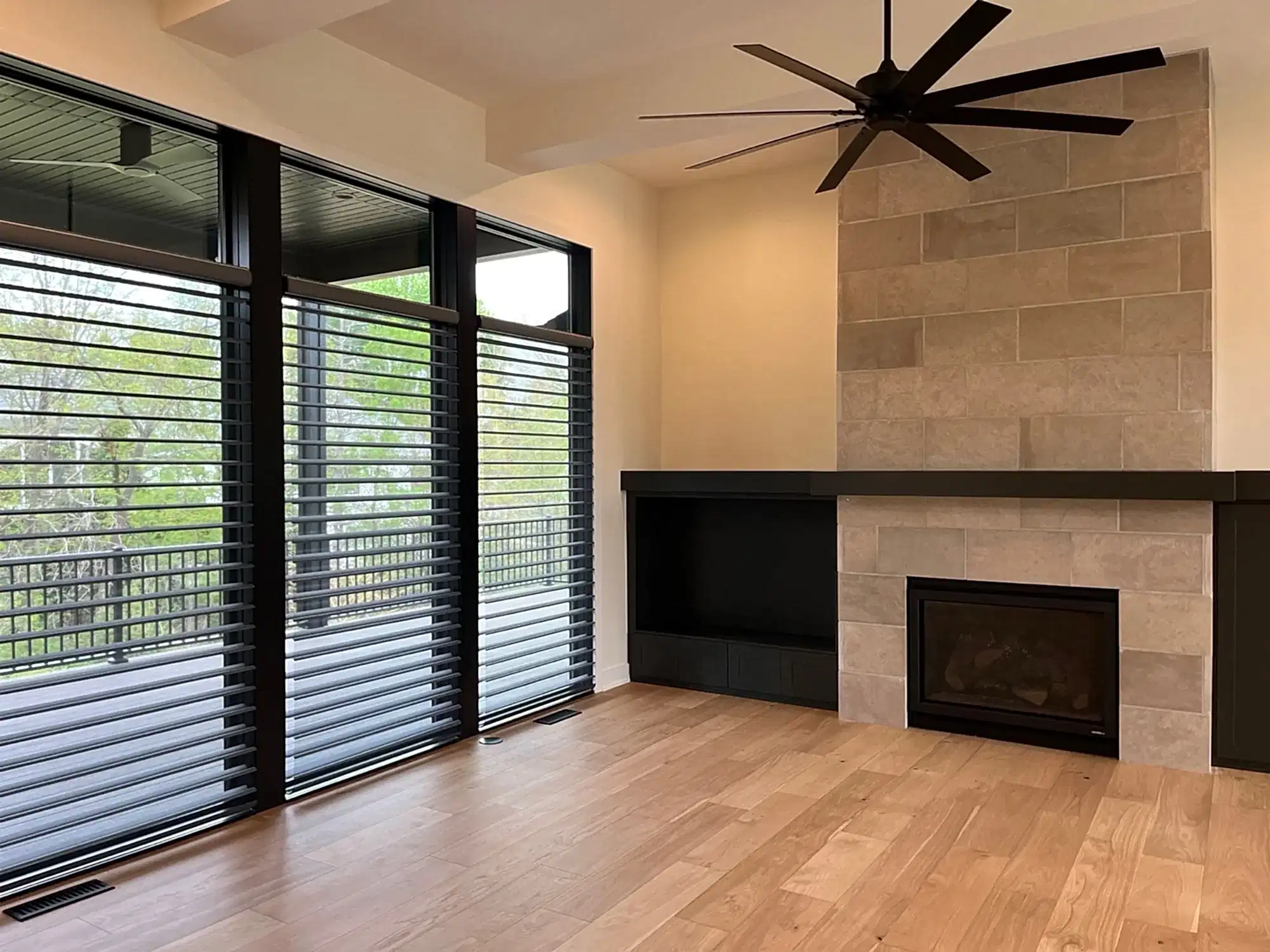 Floor-to-Ceiling Sheer Shades Floor-to-ceiling dark Silhouette sheer shades along a wall of windows in a great room with tile fireplace and ceiling fan.
